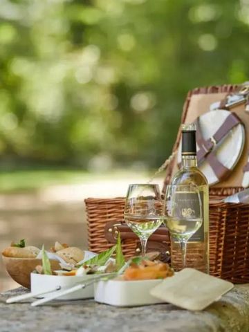 Picknickkorb mit Wein und Snacks im grünen Garten bei Château de Fonscolombe