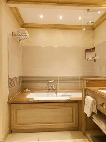 Elegantes Badezimmer mit eingelassener Badewanne und Holzvertäfelung