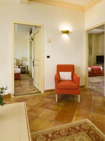 Helles Wohnzimmer einer Suite mit roten Akzenten und Holzböden