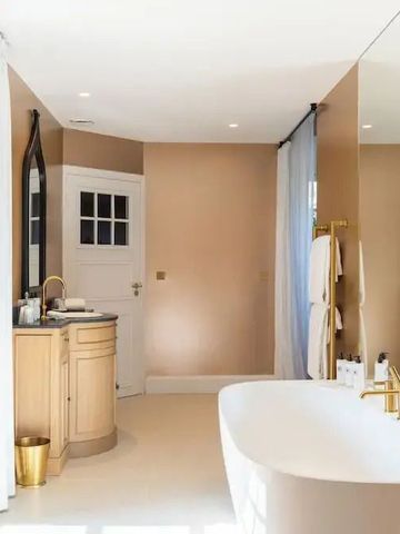 Luxuriöses Badezimmer mit freistehender Badewanne und goldenen Akzenten