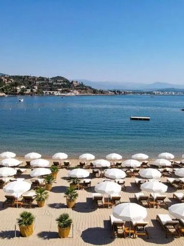 Sonnenschirme und Liegestühle am sandigen Hotelstrand mit Meerblick