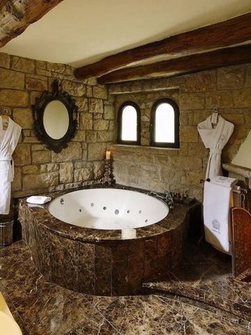 Rustikales Badezimmer mit Marmorboden und Whirlpool sowie Holzbalken