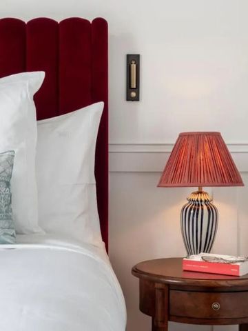 Luxuriös eingerichtetes Zimmer mit rotem Kopfteil und Nachttischlampe im Hotel