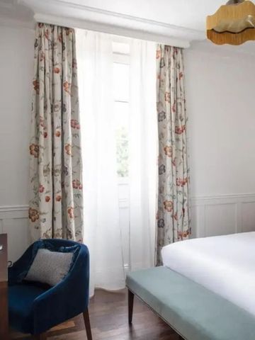 Gemütliches Schlafzimmer mit Doppelbett, Vorhängen und Schreibtisch im Hotel