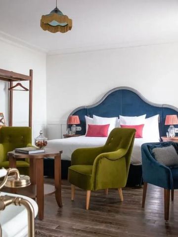 Großzügiges Hotelzimmer mit Doppelbett und gemütlichen Sitzgelegenheiten