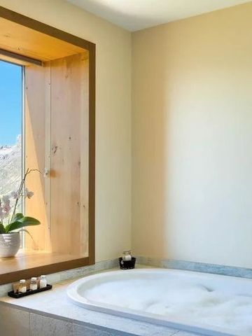 Badewanne mit Aussicht auf die Berge durch ein großes Fenster