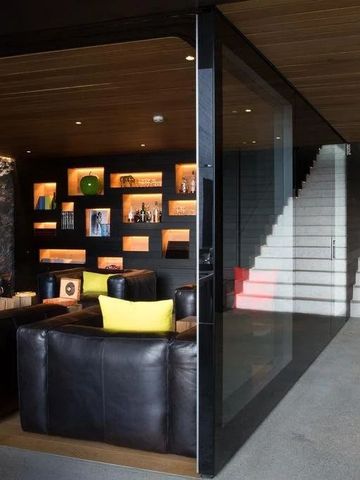 Gemütlicher Lounge-Bereich mit Ledersesseln und beleuchteten Regalen.