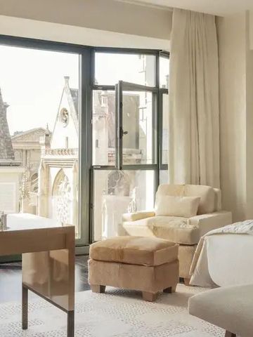 Geräumiges Zimmer mit großer Fensterfront und Ausblick auf historische Architektur.