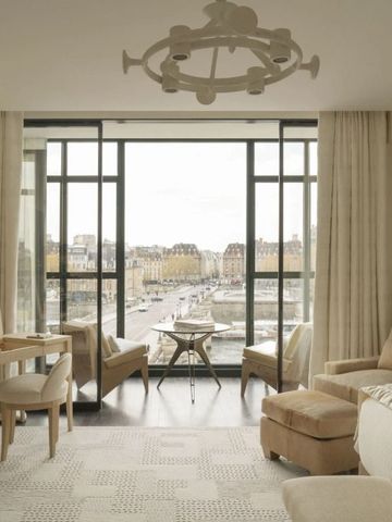 Helles Wohnzimmer mit großem Fenster und Blick über die Dächer von Paris.