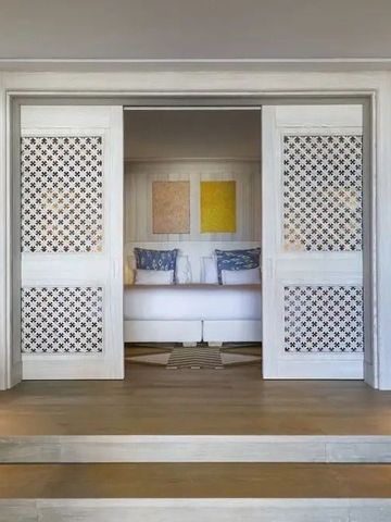 Elegantes Schlafzimmer mit offener Holztür und stilvollen Kunstwerken.