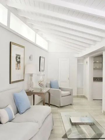 Helle Sitzecke mit weißen Möbeln und Glas-Couchtisch.