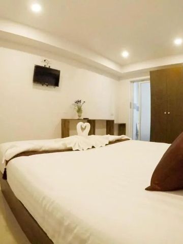 Helles Hotelzimmer mit Flachbildfernseher und dekorativen Kissen