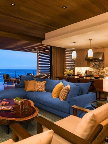 Offener Wohnbereich mit blauer Couch und Blick auf das Meer bei Dämmerung