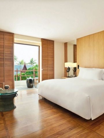 Modernes Hotelzimmer mit Holzböden und großem Bett sowie Balkon mit Blick auf Palmen