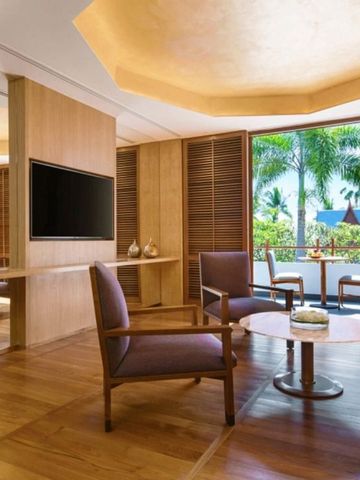 Wohnbereich mit Holzelementen und Zugang zu einem Balkon mit tropischem Gartenblick