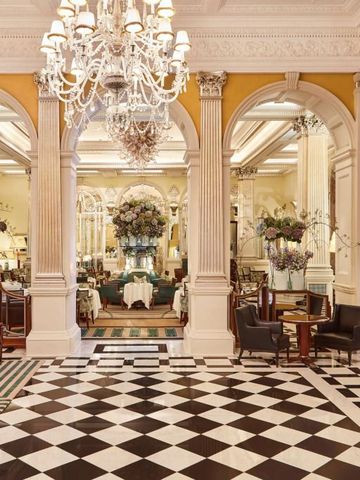 Luxuriöse Lobby mit Marmorfußboden, großen Spiegeln, Blumenarrangements und Kronleuchtern.