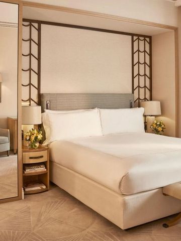 Geräumiges Hotelzimmer mit großem Bett, Spiegel, Blumen und eleganter Dekoration.