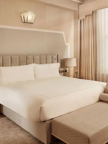 Helles Hotelzimmer mit bequemen Möbeln, großem Fenster und stilvoller Inneneinrichtung.