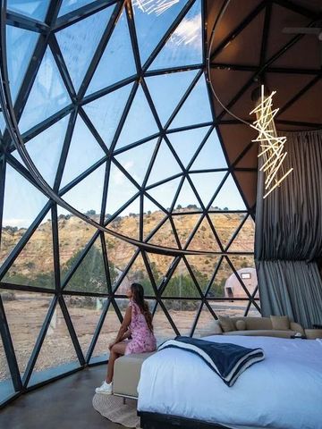 Frau sitzt im Kuppelzelt mit Blick auf die umliegende Wüstenlandschaft