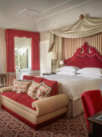 Luxuriöses Schlafzimmer mit rotem Sofa und Bett im Cliveden House.