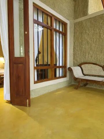 Helles Zimmer mit offener Tür zu einem kleinen Balkon und bequemer Sitzgelegenheit.