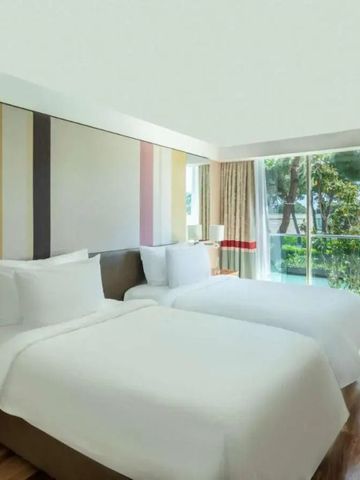 Modern eingerichtetes Zimmer mit zwei Einzelbetten und Blick auf den Garten.