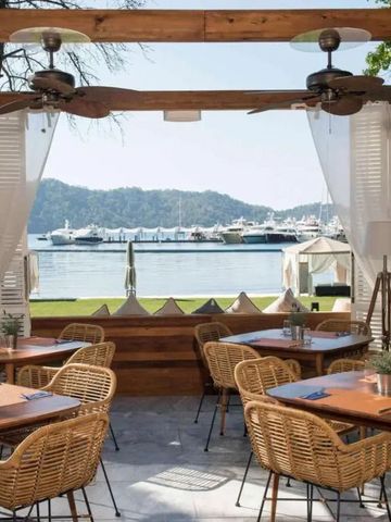 Restaurantterrasse mit Blick auf Yachthafen und Meer.
