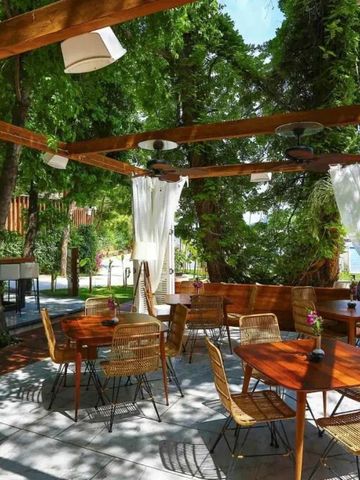 Sonnige Terrasse mit Holzmöbeln und Blick ins Grüne