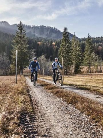 Zwei Radfahrer auf einem Schotterweg in einer idyllischen Berglandschaft