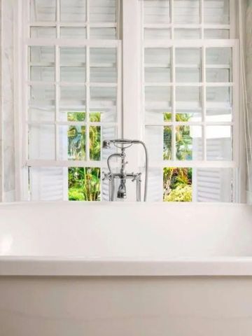 Luxuriöse Badewanne vor einem großen Fenster mit Blick auf tropische Pflanzen