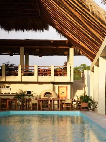 Offene Lounge mit Strohdach und Blick auf den Pool im Cocolia Hotel