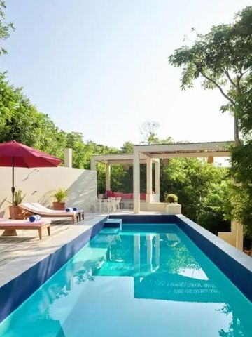 Schlanker Pool mit Liegestühlen und roten Sonnenschirmen inmitten von Grün