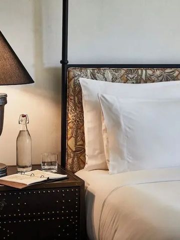 Detailaufnahme eines stilvoll eingerichteten Betts mit Lampe und Nachttisch