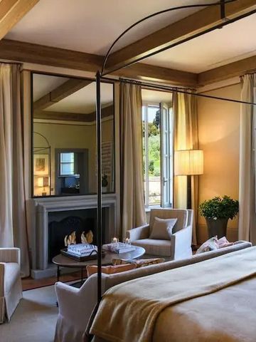 Luxuriöses Zimmer mit Himmelbett, Kamin und großen Fenstern mit Blick ins Grüne.
