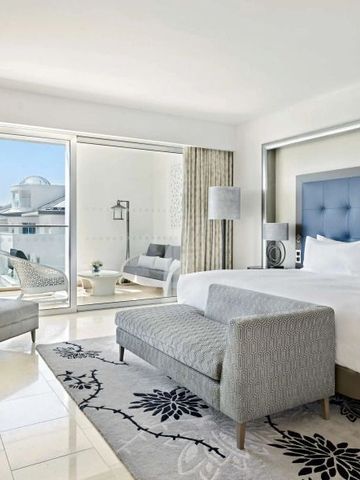 Helles Hotelzimmer mit großem Bett und Balkon mit Aussicht.