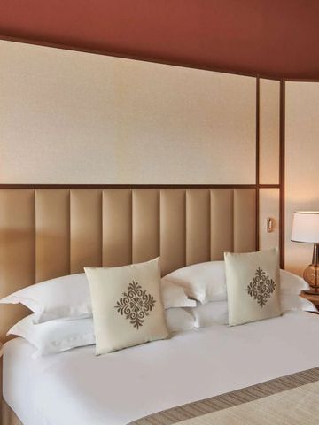 Luxuriöses Schlafzimmer mit beigem Kopfteil und eleganten Nachttischlampen.