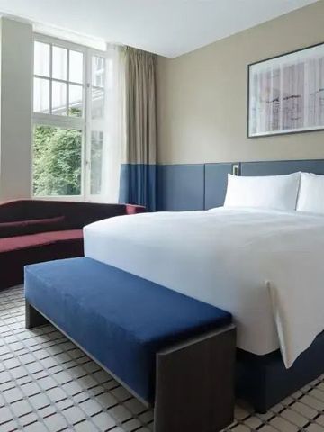 Helles Zimmer mit großem Fenster, Doppelbett und moderner Einrichtung