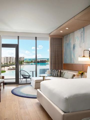 Modernes Hotelzimmer mit großem Bett und Balkon mit Seeblick