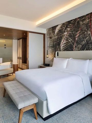 Helles Zimmer mit großem Bett und modernem Bad im Hintergrund