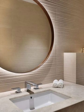 Edles Badezimmer mit großem runden Spiegel und moderner Einrichtung.
