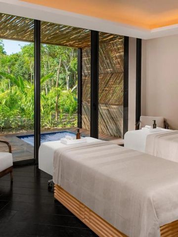 Spa-Raum mit zwei Massagetischen und Blick auf tropischen Garten