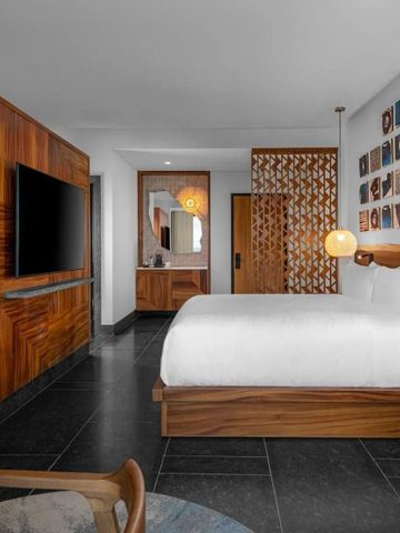 Hotelzimmer mit Holzverkleidung, Wandkunst und großem Flachbildfernseher