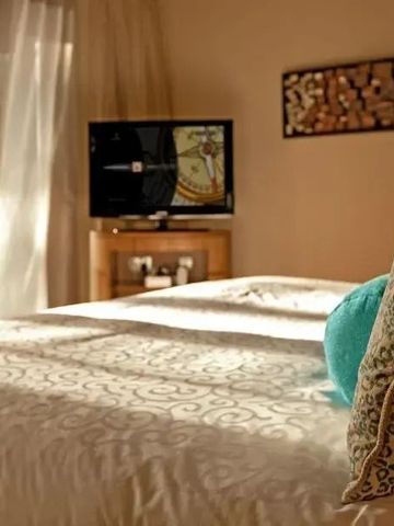 Gemütliches Zimmer mit Fernseher und deckenhohen Vorhängen für private Atmosphäre