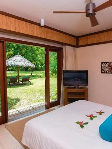 Helles Zimmer mit Glasfront und Blick auf Garten mit Sonnenschirm