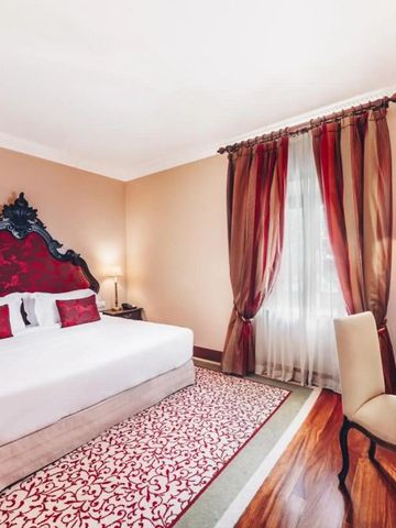 Elegantes Hotelzimmer mit luxuriösem Doppelbett und roten Akzenten