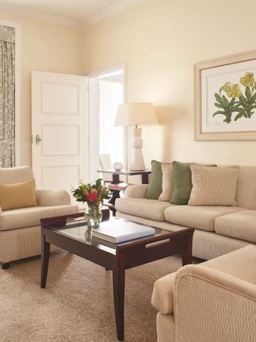 Elegantes Wohnzimmer in hellen Farben mit Sofas und Blumenarrangement