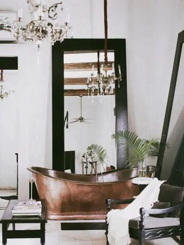 Elegantes Badezimmer mit freistehender Kupferbadewanne und großen Spiegeln