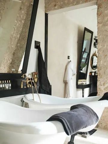 Gezackte Steinmauer und klassisches Badezimmerdesign mit Badewannen