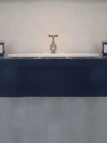 Schlichter Waschbereich mit moderner Armatur und dunklem Regal