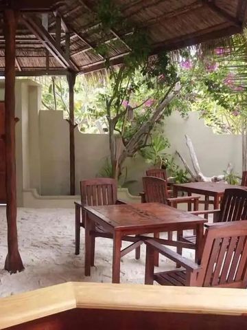 Outdoor-Sitzbereich mit Holztischen unter einem reetgedeckten Dach